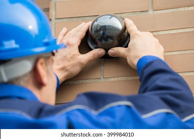 Close-up Of A Mature Male Technician Installing Camera In Building