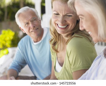 Closeup Of Mature Man With Two Cheerful Middle Aged Women Sitting On Verandah