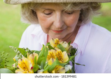 Close-up Of A Mature Woman Smelling Flowers At The Park