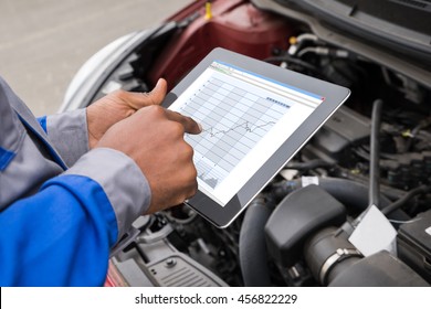 Close-up Of Mechanic With Digital Tablet Showing Graph While Examining Car - Powered by Shutterstock