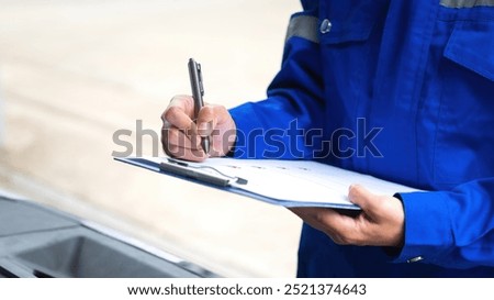 Close-up at a mechanic foreman's hand is checking on multi-point car service guideline checklist form, to verify the car service quality. Expertise working action scene, selective focus.
