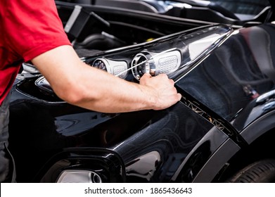 Close-up of mechanic hands dismantling the bumper of the car