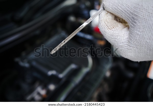 Close-up of mechanic is holding the oil dipstick to\
check the engine oil level. top view hand of a man wearing white\
gloves holding a dipstick to check and maintain the engine, check\
engine oil level