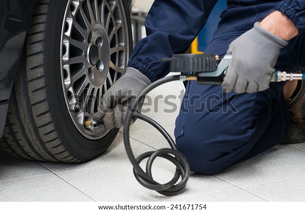 Closeup Of Mechanic At Repair Service Station\
Checking Tyre Pressure With\
Gauge