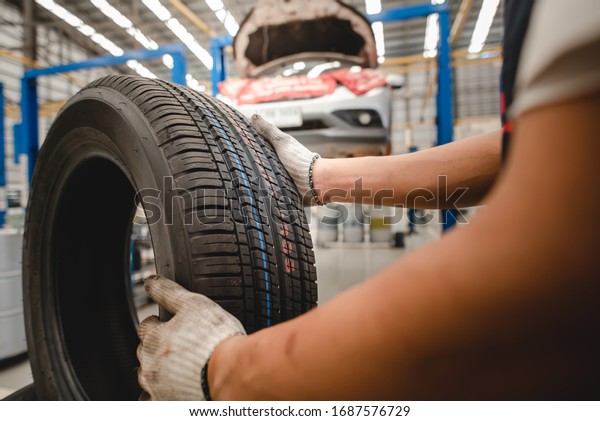 Close-up of a mechanic rolling a car tire or\
wheel To be replaced with a car that is used in the garage that\
works in the factory or service center Change winter tires before\
the rainy season.