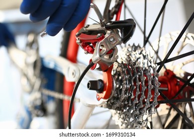 Close-up of mechanic serviceman installing assembling or adjusting bicycle gear on wheel in workshop. Technical expertise. Bike maintenance and repair service concept
