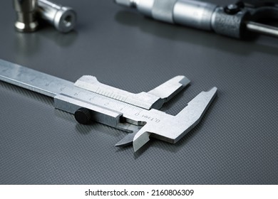 Closeup of a mechanical caliper, against the background of a micrometer and steel parts. Industrial background.