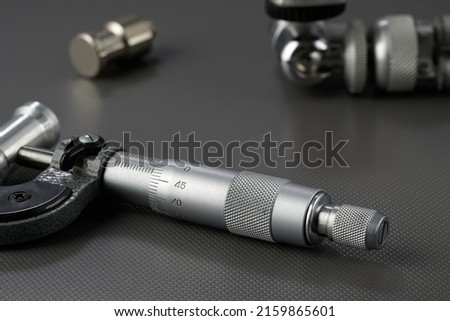 Closeup of a mechanical micrometer against the background of other measuring instruments. Industrial theme.
