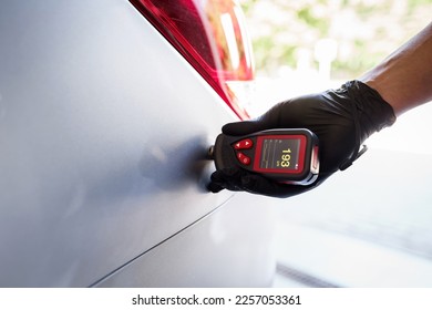 Close-up of a mechanic's hand holding a magnetic thickness gauge. Instrument for measuring paint thickness. Checking a car at a service station - Shutterstock ID 2257053361