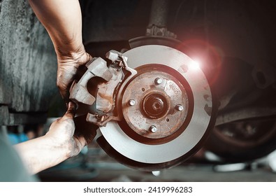 Close-up of a mechanic's hands working on a car's disc brake system, highlighting maintenance and repair.
 - Powered by Shutterstock