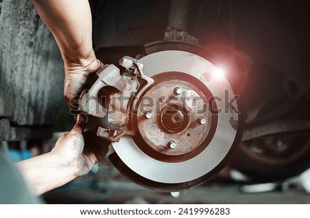 Close-up of a mechanic's hands working on a car's disc brake system, highlighting maintenance and repair.
