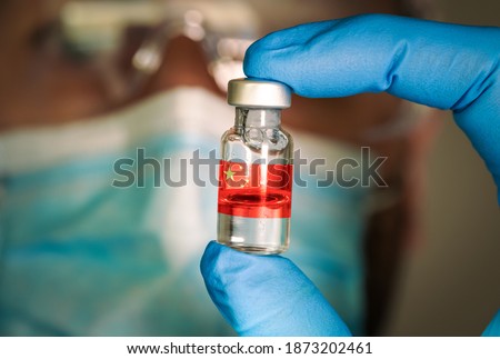 Close-up of medical vial with the flag of China and a blurred doctor on the background. Selective focus. Concept of Covid vaccination campaign in China