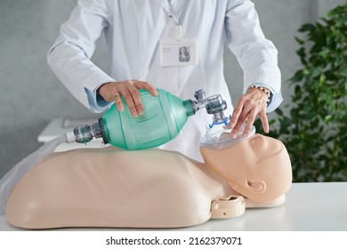 Close-up of medical worker in white coat demonstrating reanimation of patient on mannequin with oxygen mask - Powered by Shutterstock