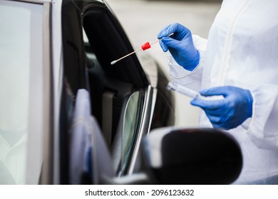 Closeup of medical worker's hands in gloves performing drive thru swab sample collection,driver in car in mobile testing center getting health check through vehicle window,Coronavirus PCR test process