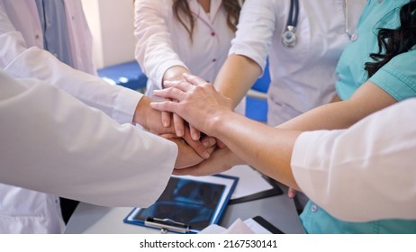 Close-Up of Medical Workers Stack Hands on the Table Together for Support at Work. Team of Doctors at Modern Hospital. Team spirit at modern at Clinic.