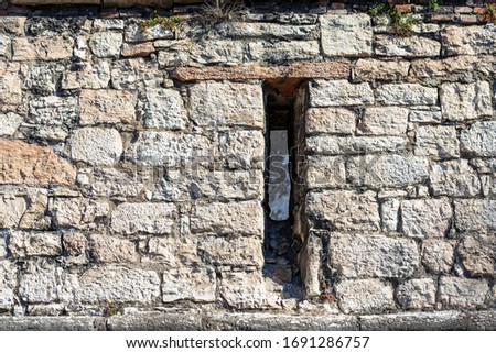 Close-up of a medieval castle wall with an arrowslit or loophole. Castello del Buonconsiglio or Castelvecchio in Trento city. Trentino Alto Adige, Italy, Europe