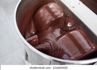 Closeup Of Melted Chocolate Being Turned In A Large Stainless Steel Mixing Machine In An Artisanal Chocolate Making Factory