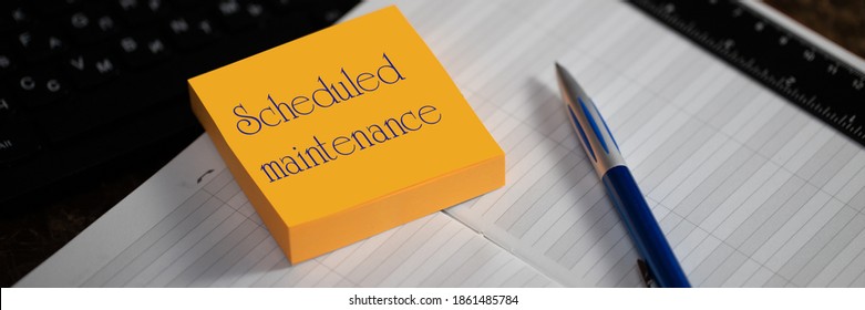 Close-up of a memory stick with the word scheduled maintenance. Selective focus. Calendar scheduler in workplace manager. Ensuring compliance with the preventive maintenance schedule