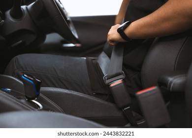 Close-up Men's hand fastens the seat belt of the car while sitting inside the car before driving and take a safe journey - Powered by Shutterstock