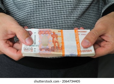 Close-up men's hands hold a wad of Russian money five thousand bills.