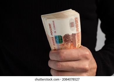 Close-up of men's hands holding a wad of Russian money with five-thousand-dollar bills. High quality photo