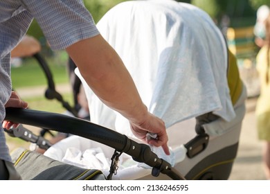 Close-up of men's hands with a stroller. A young father, straightens the cape on the stroller. Father's Day Concept. High quality photo