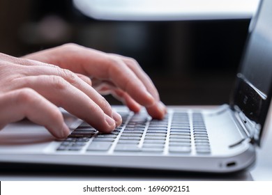 Close-up Of Men's Hands Typing On Laptop Keyboard At The Desk. Unrecognizable Man Is Writing Email On Laptop At The Office Or Home.