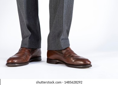 Closeup Of Mens Legs Wearing Brown Penny Loafers. Against White Background. Horizontal Image