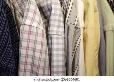 close-up of mens long sleeve dress business work attire shirts lined up in a row closet plaid check solid oxford tops assortment texture wardrobe closet background