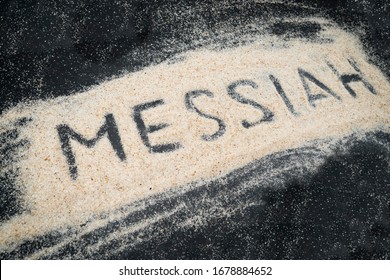 Closeup of MESSIAH text written on white sand with black wooden background - Shutterstock ID 1678884652