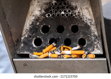 Close-up of a metal ashtray with cigarette butts in the city