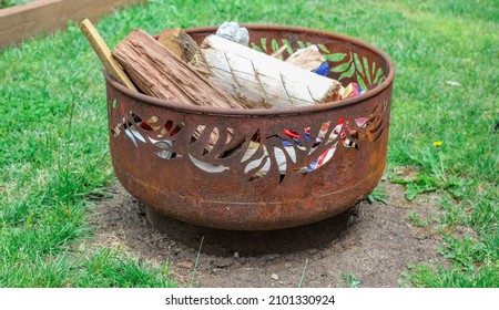 A Closeup Of A Metal Basket Outdoors With Wood Inside It - Ready For A Backyard Campfire