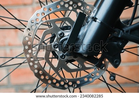 Close-up of a metal brake disc on the front wheel of a mountain bike. Outdoors.
