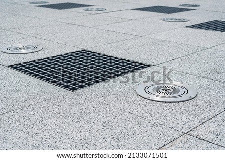 Close-up, Metal caps for outdoor water drain and Sprinkler for a fountain. Against the background of paving slabs of gray granite