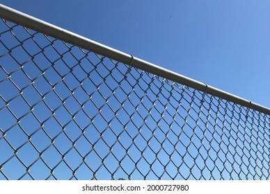 Closeup of a metal chain link fence with a clear blue sky background