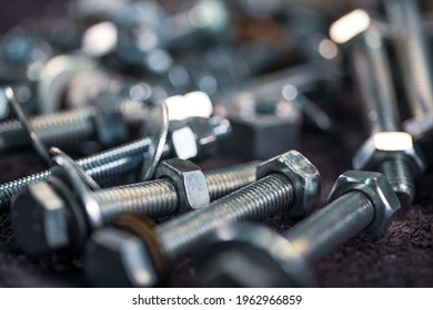 Close-up metal chrome bolts and nuts in a chaotic order. Background concept for fasteners and construction topics. Repair and spare parts concept