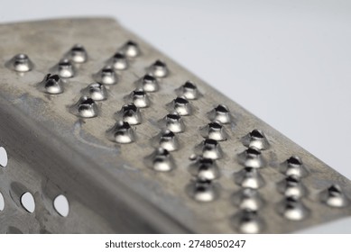 Close-up of a metal grater surface with sharp holes.
