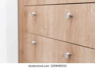 closeup of metal handle on wooden drawer of cabinet in bedroom, new modern cupboard in furniture store or minimalists apartment