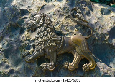 Close-Up Of metal Lion Statue placed on a stone wall