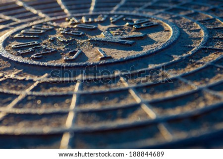 Close-up of the metal manhole cover in the sunshine.