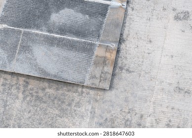Close-up of metal mesh panel with rust stains. Metal mesh panel shows rust stains on concrete surface. Panel rests on textured concrete ground. Visible rust spots on metal edges