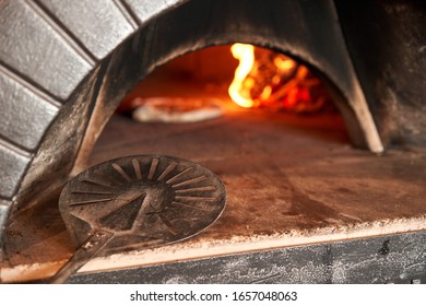 closeup of a metal shovel. Baked tasty margherita pizza in Traditional wood oven in Naples restaurant, Italy. Original neapolitan pizza. Red hot coal.