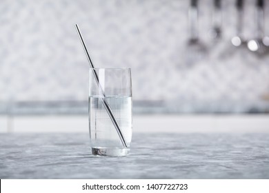 Close-up Of Metal Straw In Transparent Glass Of Water On Kitchen Counter