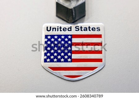 Close-up of a metallic badge featuring the United States flag in a shield design with the words 