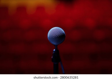Close-up microphone from the performer’s perspective before stepping into the spotlight. The blurred audience and vibrant red stage lighting create a powerful concept of live music, artistic ambition, audience connection, confidence, fame, and unforgettable concert experiences.