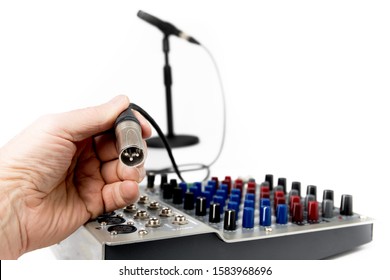 closeup of a microphone XLR audio cable  being plugged into a sound mixing board