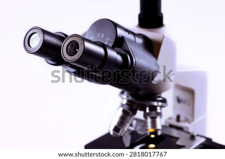 Close-up of microscope eyepieces and objective lenses on a professional laboratory microscope. Scientific optical equipment isolated on a white background.