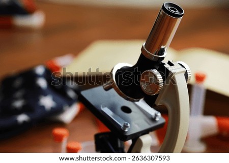 Close-up of a Microscope on a Laboratory Table with Test Tubes and an Open Book
