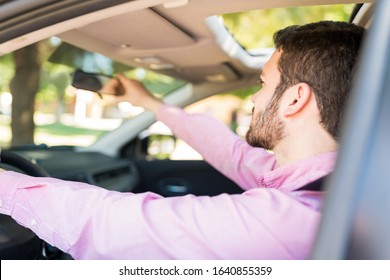 Closeup Of Mid Adult Latin Man Adjusting Rearview Mirror In Car