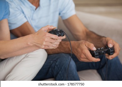 Close-up mid section of a couple playing video games in the living room at home